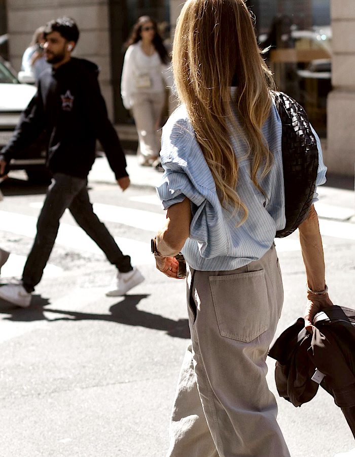 Femme portant une chemise bleu clair aux manches retroussées avec un pantalon ample